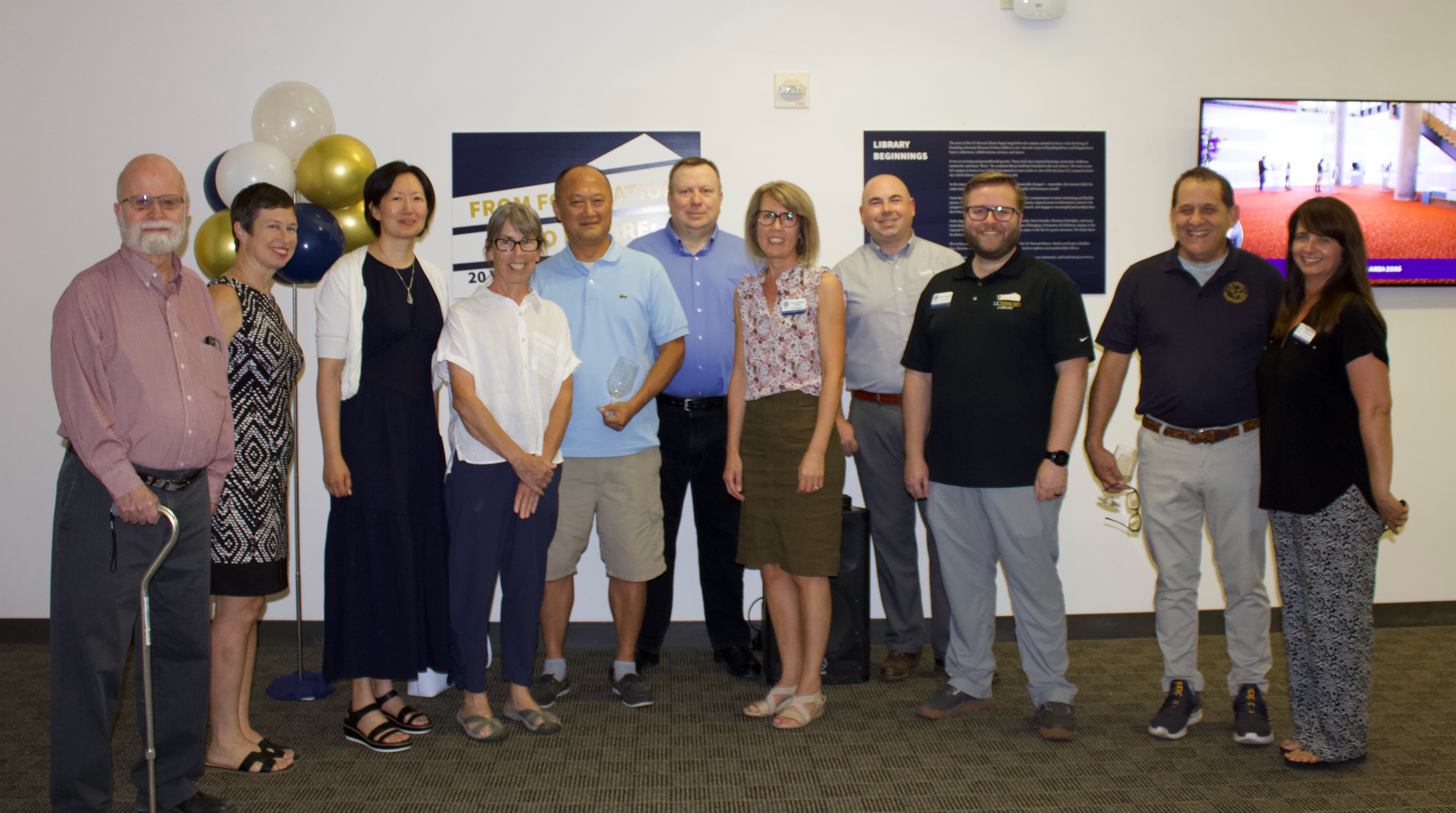 Founding staff stand in a line in front of the exhibit and face the camera