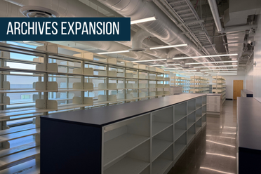 Tall shelving for books in background with half-height enclosed shelving in front, stretch to back of rooml; exposed ducting runs length of ceiling; titled Archives Expansion at upper left