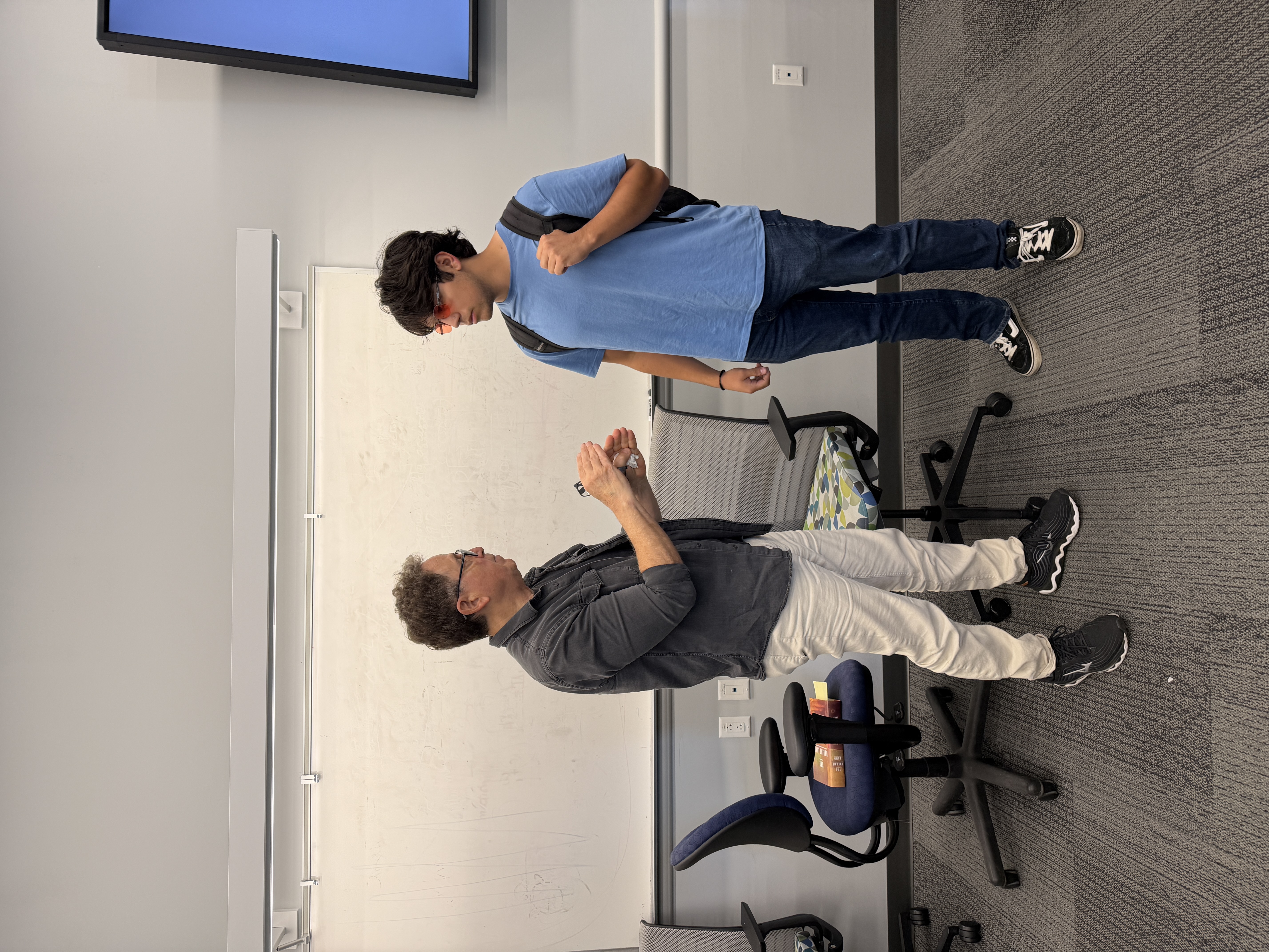 Mark Arax and student stand and face each other talking in a classroom