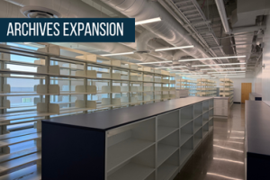 Tall shelving for books in background with half-height enclosed shelving in front, stretch to back of rooml; exposed ducting runs length of ceiling; titled Archives Expansion at upper left