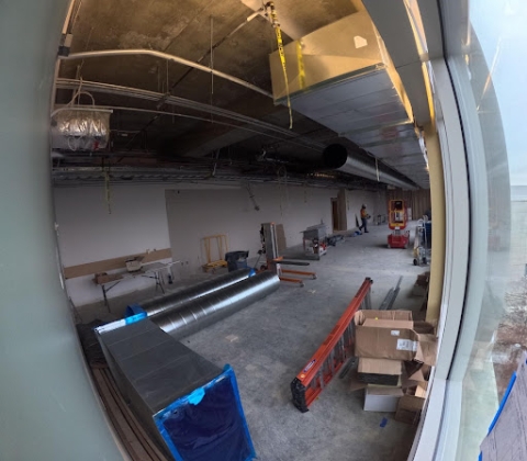 4th floor archives space under construction with filled in wall, exposed ducting in ceiling, and materials on floor