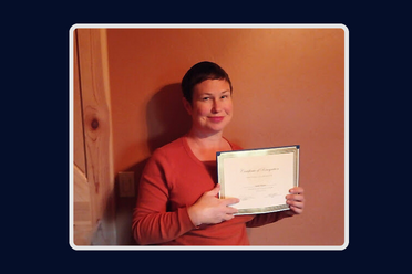 woman with short brown hair in a red sweater holding a certificate and smiling 